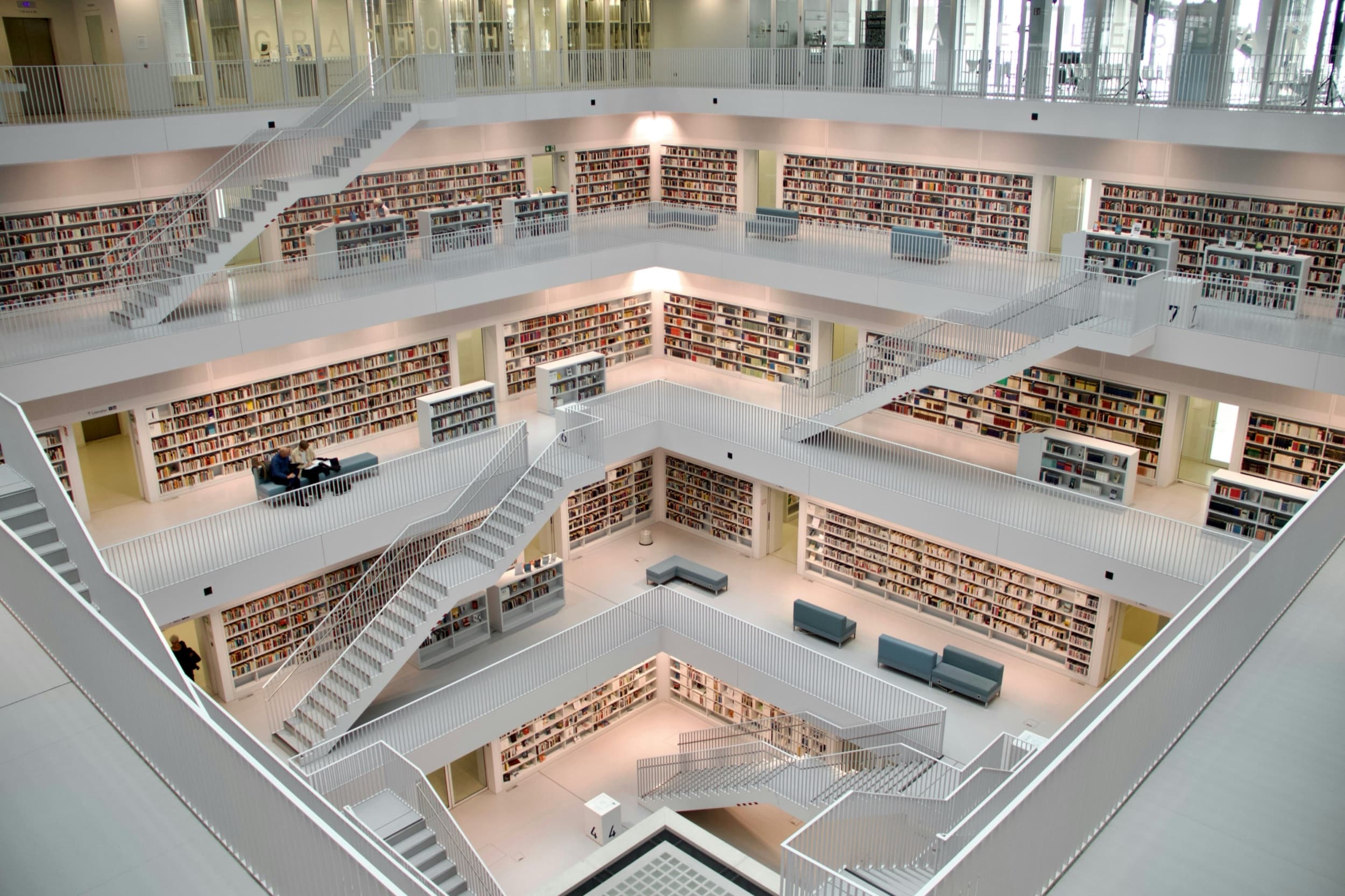 Weiße Galerien einer modernen Bibliothek mit gleichmäßig gefüllten Bücherregalen und Treppen, von oben