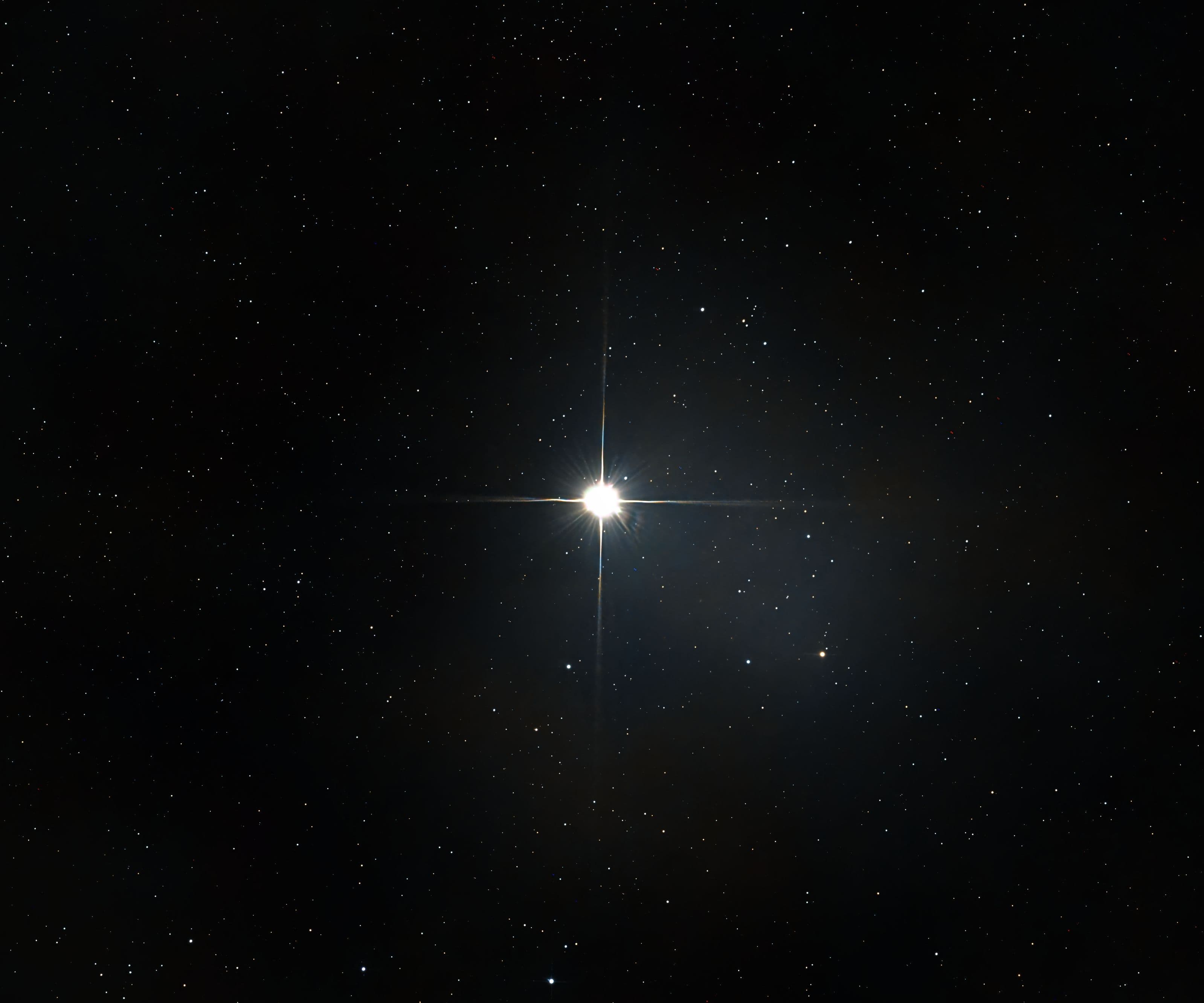 Hell strahlender Stern mit Lichtkreuz vor einem Sternenfeld
